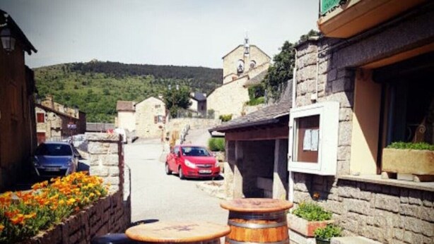A narrow street with stone buildings, wooden barrels, and a red car parked on the side. - O'Friendly Gold Cottage 14 (Dorres)