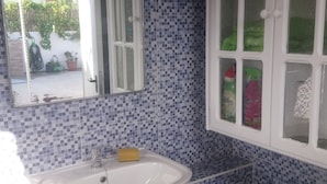 Un baño con un lavabo blanco, un espejo y una ventana.