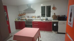 Una cocina compacta con armarios rojos, estufa a gas, microondas y un lavamanos.