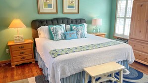 A bedroom with a bed, bedside tables, a bench, and a wardrobe. - Cabana III:  Perfect getaway for two that offers a shared pool. (Ocracoke)