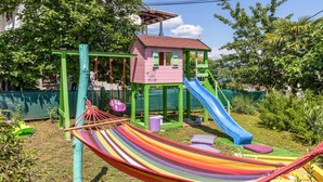 Un parque infantil con un tobogán colorido, columpios y una hamaca.