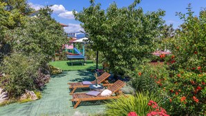 Un jardín con zona de juegos, una hamaca y sillones de descanso.