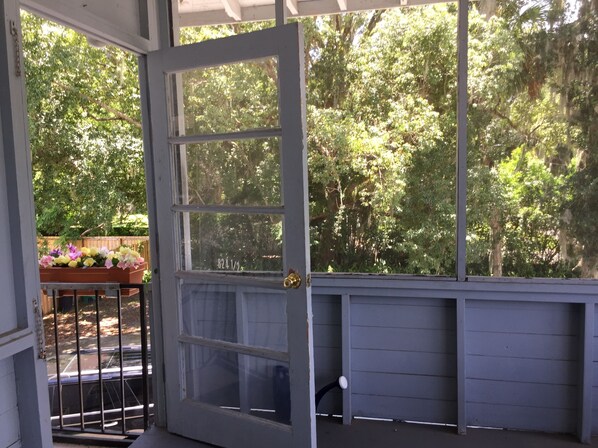 A covered porch with a wooden door and a view of a garden.