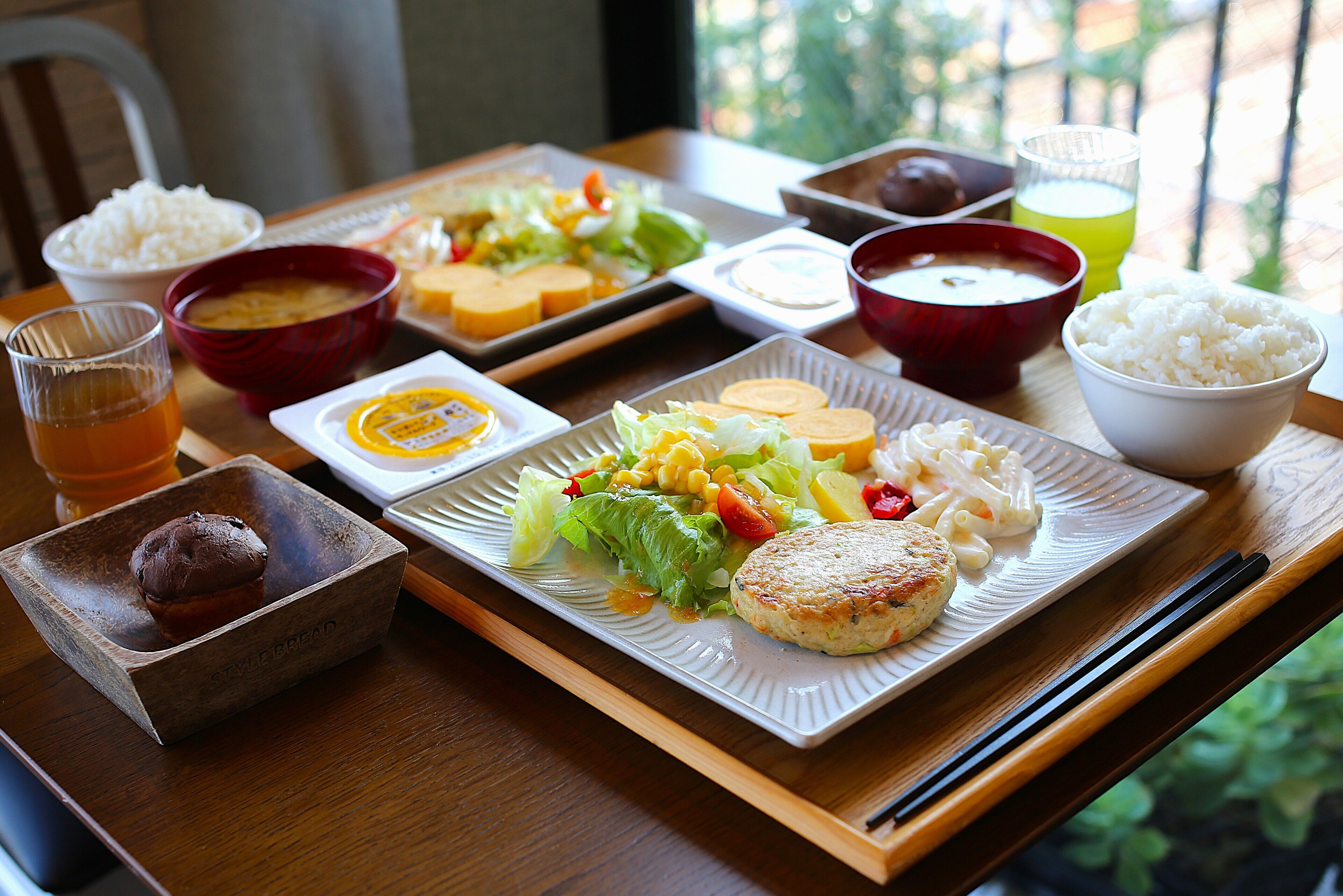 A tray with various dishes including rice, soup, and a plate with vegetables and a patty.