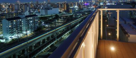 A high-rise building with a view of a cityscape, including a prominent tower and a busy highway.