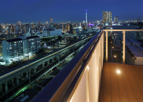A high-rise building with a view of a cityscape, including a prominent tower and a busy highway.