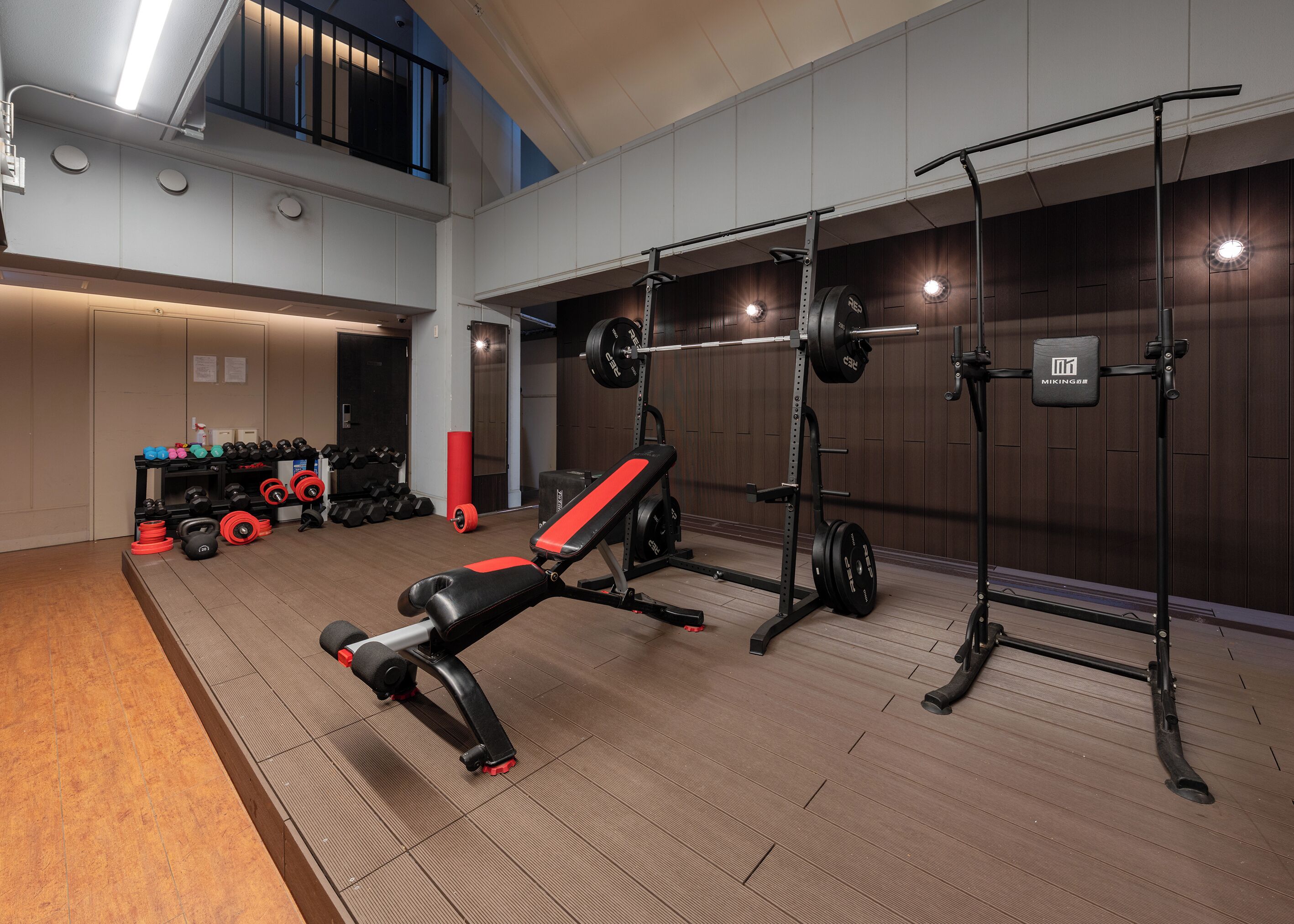 A gym with weightlifting equipment, a bench, and a mirror.