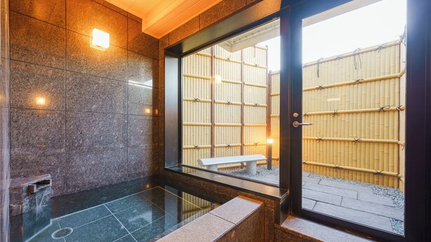 A modern bathroom with a stone floor, a bench outside the window, and a view of a bamboo fence. - TOKYO CITY VIEW HOTEL TABATA-STATION (Tokyo)