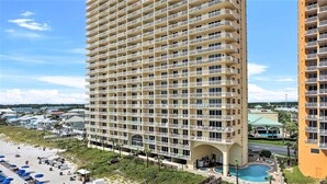 Ein Hochhaus-Hotel mit mehreren Balkonen, einem Poolbereich und Zugang zum Strand.