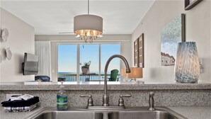 Eine Küche mit doppeltem Waschbecken, einer Chandelüster und Blick aufs Meer.