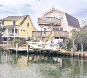 A boat docked at a pier with a house in the background.