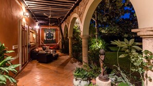 Un espacio al aire libre techado con una disposición de asientos, una estatua y un mural en la pared.