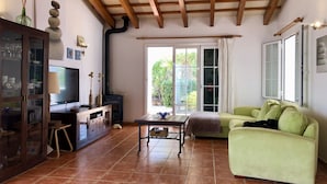 Un salon avec un plafond en bois, un t éléviseur, un canapé vert et un sol carrelé.