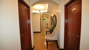A hotel hallway with wooden doors, a reception desk, and a mirror.