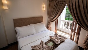 A neatly made bed with a headboard, two wall-mounted lights, and a window with curtains.