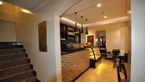 A modern interior with a curved staircase, a counter with a patterned wall, and a dining area with chairs and a table.