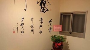 A traditional room with a dining table, chairs, a potted plant, and calligraphy on the wall. - Teapot House (Jinning)