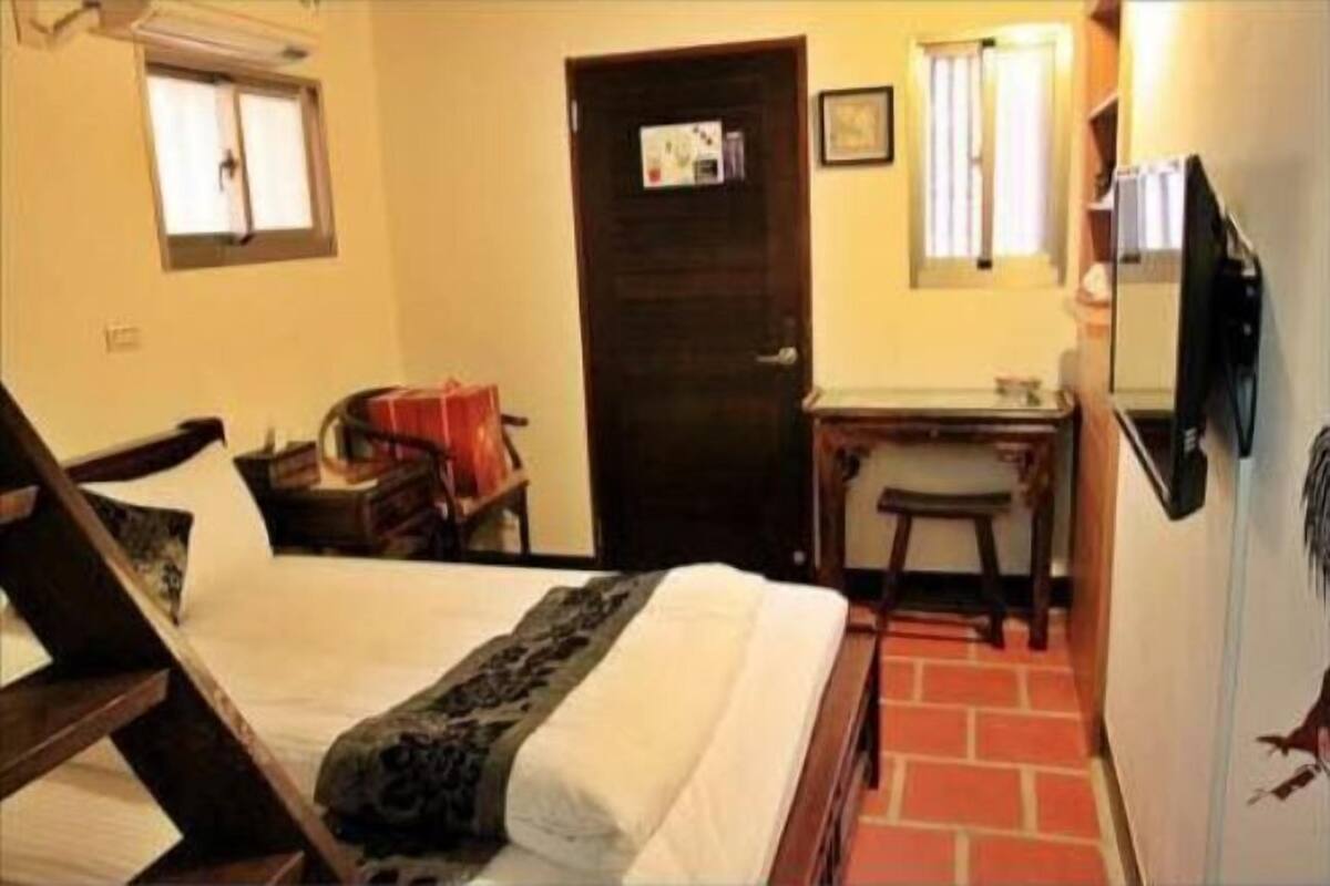 Un dormitorio con cama, escritorio, silla, armario y puerta.