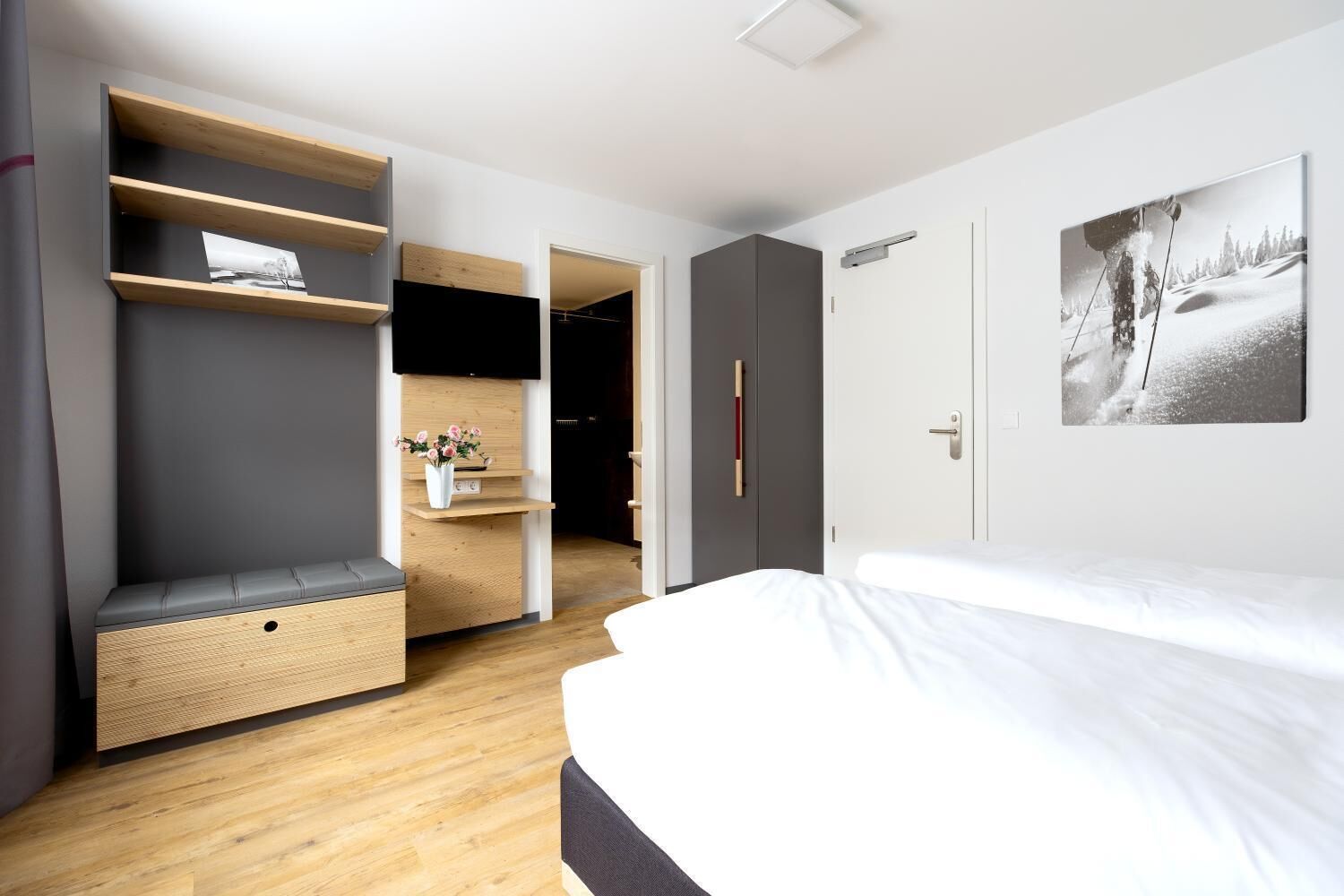 Un dormitorio moderno con cama, estanterías empotradas, un pequeño escritorio y un armario.