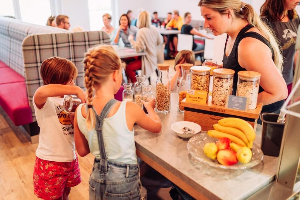 Un groupe de personnes est assis au comptoir d’un bar où l’on sert le petit-déjeuner, et devant eux se trouvent divers aliments et récipients.