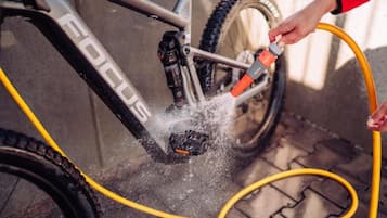 A person cleaning a bicycle with a water hose.