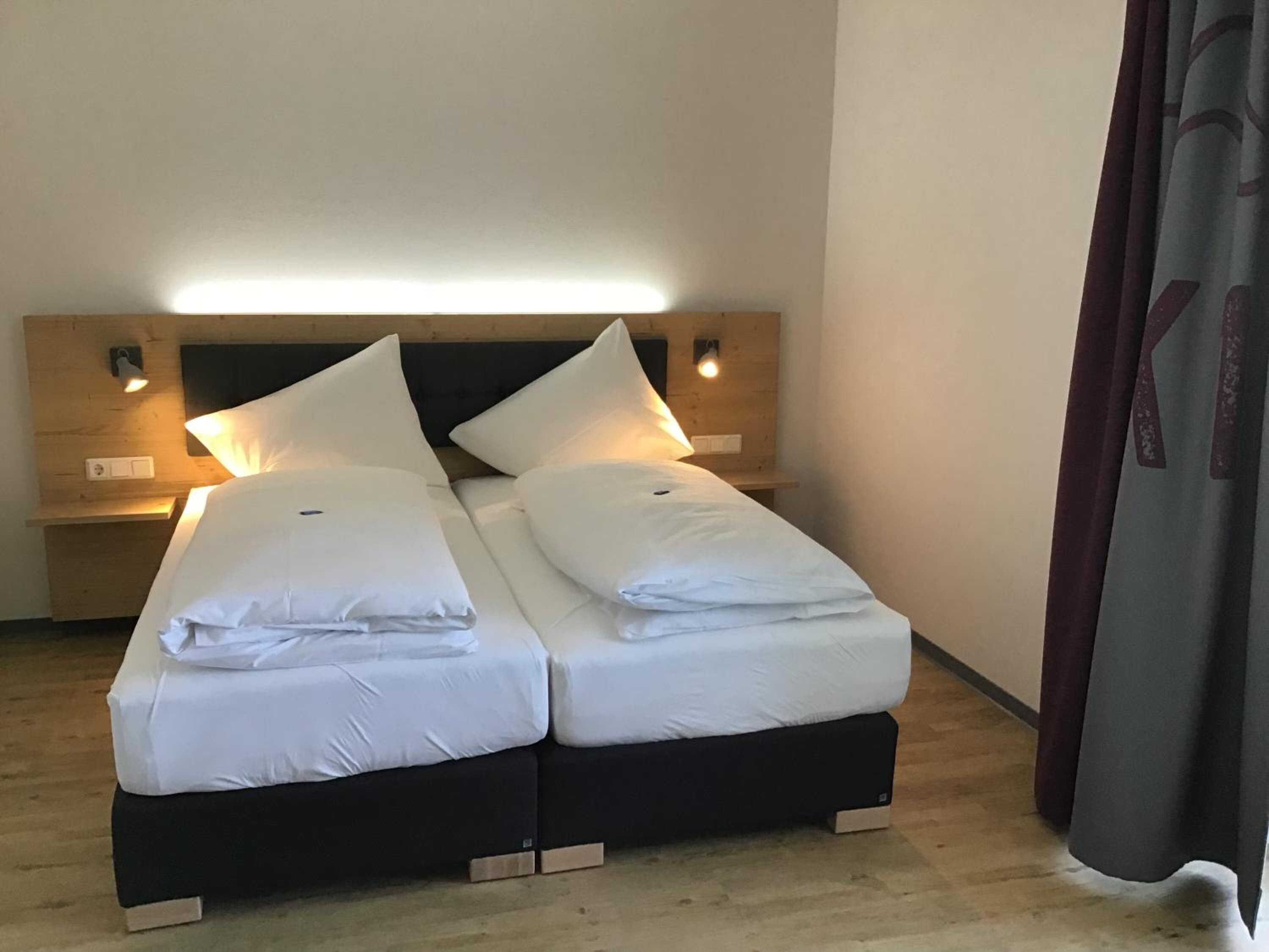 A double bed with white linens and two bedside tables, each with a lamp.