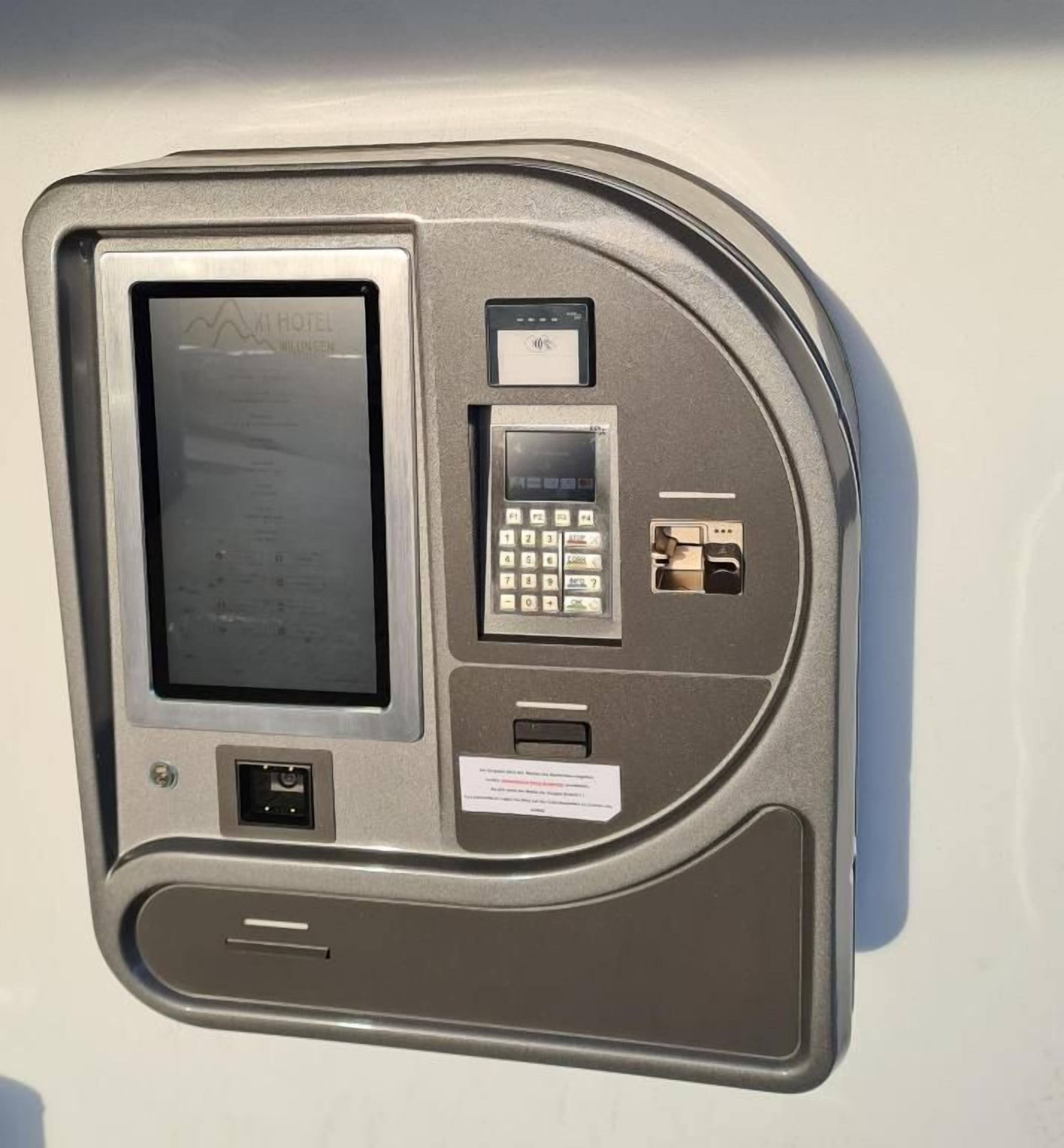 A wall-mounted electronic device with a screen, keypad, and USB ports.