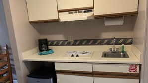 A compact kitchenette with a coffee maker, two plates, a sink, and a trash bin. - Olde Gatlinburg 203 is a beautiful condo with private balcony located in downtow (Gatlinburg)