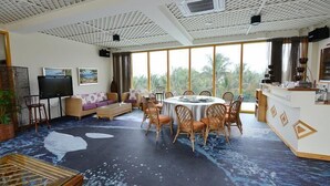 A spacious room with a large window, a round dining table with chairs, a sofa, a TV, and a reception desk. - Tung Lodge - Taitung Branch (Chenggong)