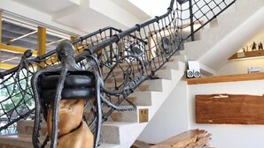 A staircase with a metal railing and a wooden sculpture at the bottom. - Tung Lodge - Taitung Branch (Chenggong)