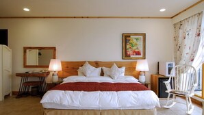 A hotel room with a large bed, two bedside lamps, a wooden headboard, a small desk with a chair, a television, and a window with curtains. - Tung Lodge - Taitung Branch (Chenggong)