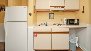 Eine kleine Küche mit Kühlschrank, Mikrowelle, Spüle und Holzschränken.