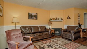 Ein Wohnzimmer mit einem braunen Ledersofa, einem rosa Sessel und einem Kamin.