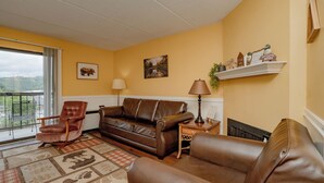 Ein Wohnzimmer mit braunem Ledersofa, einem Holzsesseln und einem gemusterten Teppich.