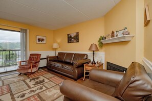 A living room with a brown leather sofa, a wooden armchair, and a patterned rug. - OGP606 downtown near Ripley's Aquarium & Anakeesta (Gatlinburg)