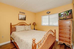 A bedroom with a wooden bed, a dresser, a window with blinds, and a wall-mounted TV. - OGP606 downtown near Ripley's Aquarium & Anakeesta (Gatlinburg)