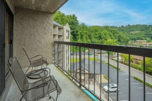 Ein Balkon mit Metallstühlen und Blick auf einen Parkplatz sowie Grünflächen.
