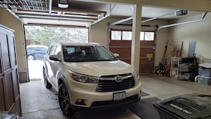 A white SUV parked in a garage with a concrete floor, a garage door, and a trash bin labeled "Garbage Only". - Fall hiking & mtn biking from front door! Large Chef's kitchen, serene backyard  (Bend)