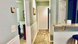 A hallway with wooden flooring, white walls, and a door at the end. - 1st Floor! Corner Unit! 3 Bedrooms! True Blue Golf Course, Minutes from Beach! (Pawleys Island)