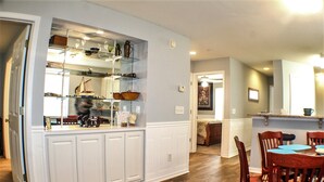 A kitchen with a built-in bar area, wooden cabinets, and a dining table with chairs. - 1st Floor! Corner Unit! 3 Bedrooms! True Blue Golf Course, Minutes from Beach! (Pawleys Island)