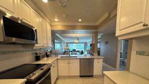 Una cocina moderna con armarios blancos, microondas integrado, electrodomésticos de acero inoxidable y una isla central con pileta.