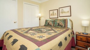 A bedroom with a large bed, a nightstand, a lamp, and two framed pictures on the wall. - OGP502 downtown near Ripley's Aquarium & Anakeesta (Gatlinburg)