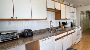 A kitchen with white cabinets, a toaster, a dishwasher, and a sink.
