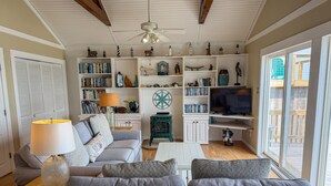 A living room with a sofa, a coffee table, a TV, and a bookshelf filled with books and decorative items.