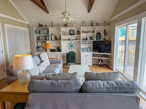 Ein Wohnzimmer mit einer Couch, einem Couchtisch, einem Fernseher und einem Bücherregal voller Bücher und Dekoration.