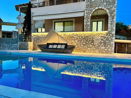 Una piscina al aire libre, sombrillas, sillones reclinables de piscina