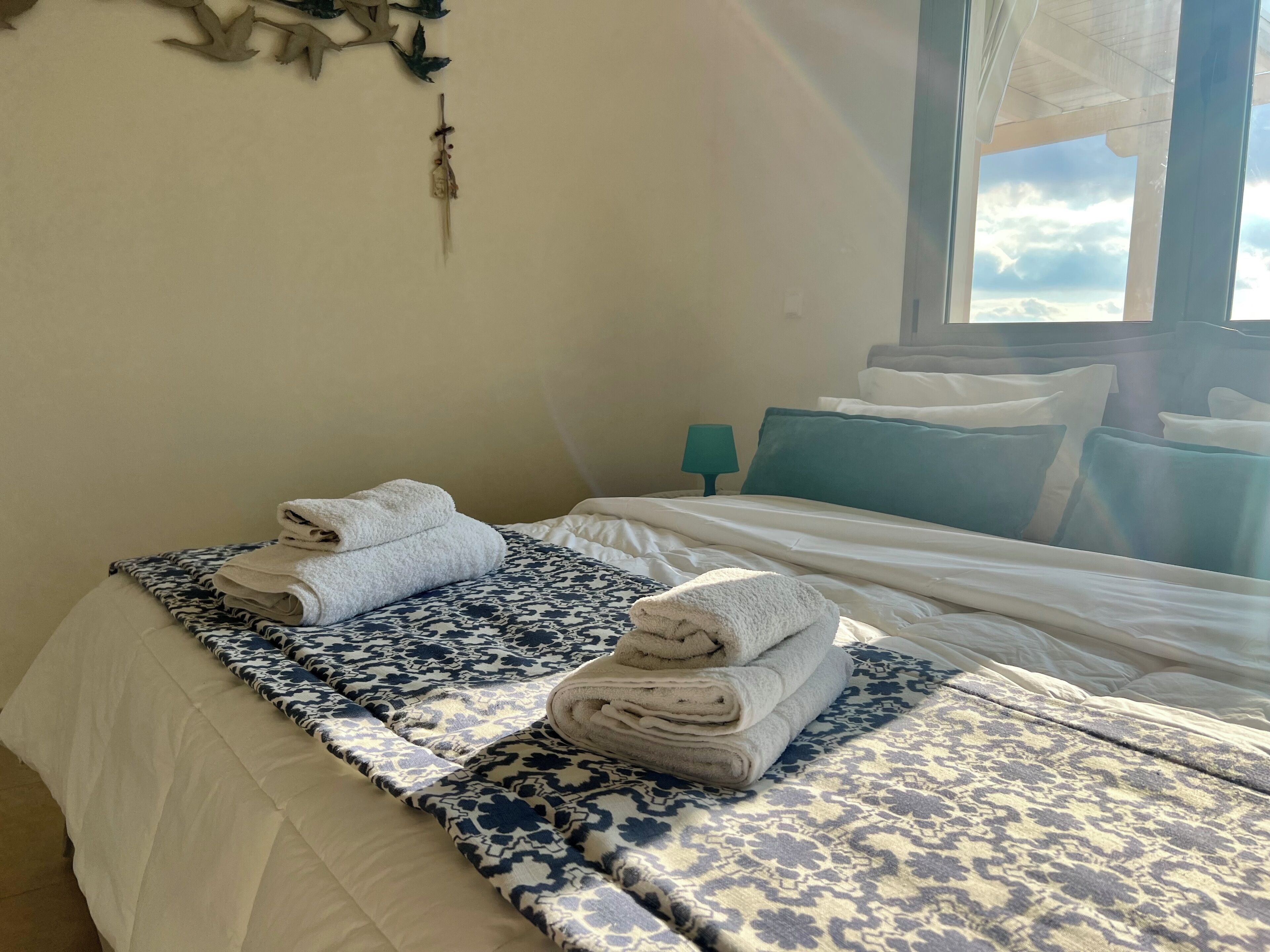 Una cama bien hecha con una colcha estampada y dos toallas dobladas.