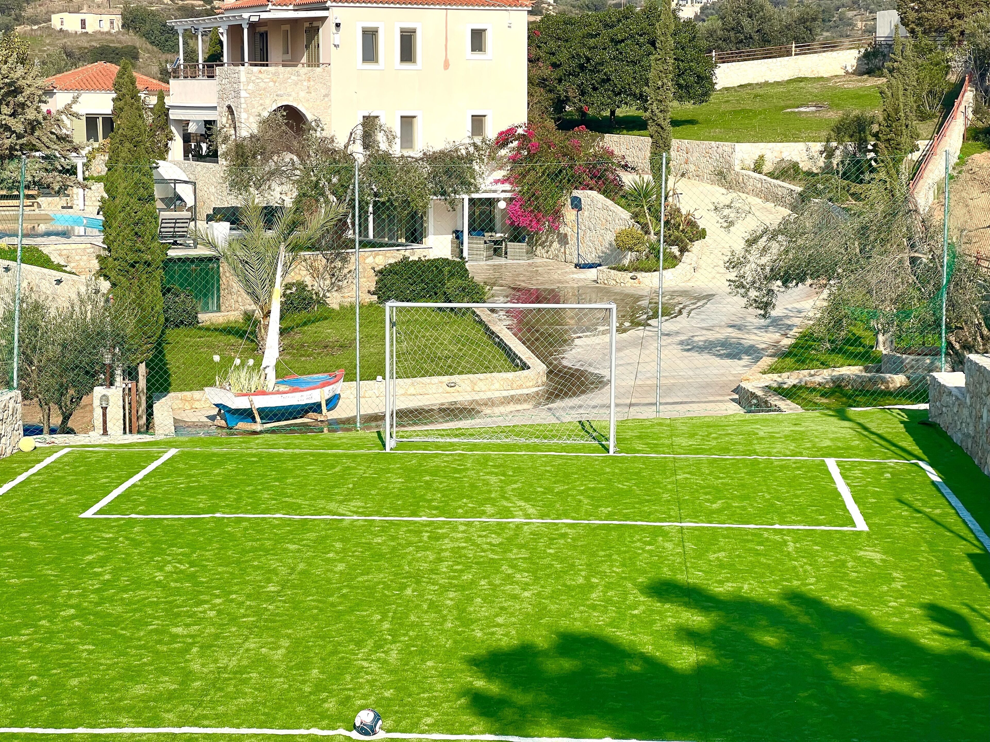 A soccer field with a goalpost, surrounded by a stone wall and greenery.