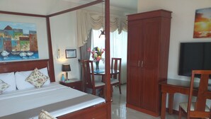 A hotel room with a four-poster bed, wooden furniture, a desk, and a television. - Ocean Breeze Resort (Toledo City)