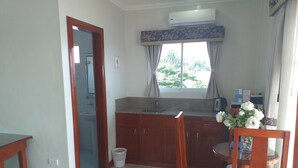 A compact kitchen with wooden cabinets, a sink, and a window with curtains. - Ocean Breeze Resort (Toledo City)